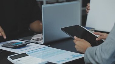 İş adamları mali istatistikleri tartışıyor ve ofiste hesap makinesi kullanıyorlar