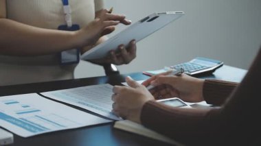 Beyaz gömlekli ve gri takım elbiseli genç bir kadın belgeyi elinde tutuyor.