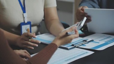 Kapat. Genç bir iş adamı ve bir iş kadını bir kalemle belgeyi tartışıyorlar..
