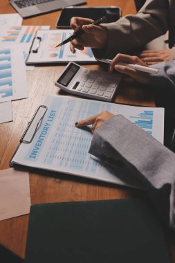 Group of confident business people point to graphs and charts to analyze market data, balance sheet, account, net profit to plan new sales strategies to increase production capacity.