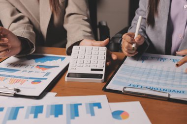 Group of confident business people point to graphs and charts to analyze market data, balance sheet, account, net profit to plan new sales strategies to increase production capacity.