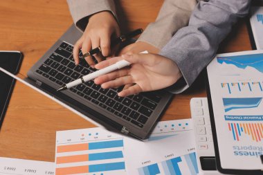 Group of confident business people point to graphs and charts to analyze market data, balance sheet, account, net profit to plan new sales strategies to increase production capacity.