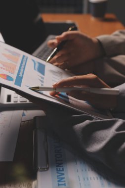 Group of confident business people point to graphs and charts to analyze market data, balance sheet, account, net profit to plan new sales strategies to increase production capacity.