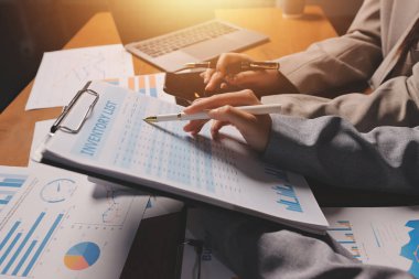 Group of confident business people point to graphs and charts to analyze market data, balance sheet, account, net profit to plan new sales strategies to increase production capacity.