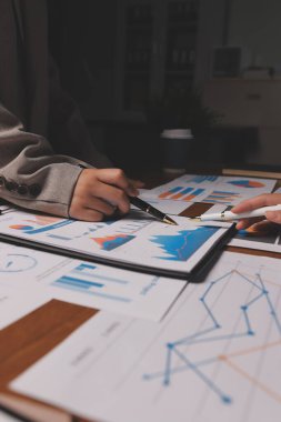 Group of confident business people point to graphs and charts to analyze market data, balance sheet, account, net profit to plan new sales strategies to increase production capacity.