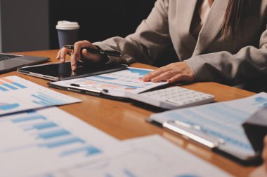 Group of confident business people point to graphs and charts to analyze market data, balance sheet, account, net profit to plan new sales strategies to increase production capacity.