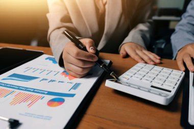 Group of confident business people point to graphs and charts to analyze market data, balance sheet, account, net profit to plan new sales strategies to increase production capacity.