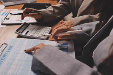 Group of confident business people point to graphs and charts to analyze market data, balance sheet, account, net profit to plan new sales strategies to increase production capacity.