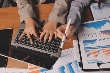 Group of confident business people point to graphs and charts to analyze market data, balance sheet, account, net profit to plan new sales strategies to increase production capacity.