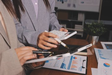 Group of confident business people point to graphs and charts to analyze market data, balance sheet, account, net profit to plan new sales strategies to increase production capacity.