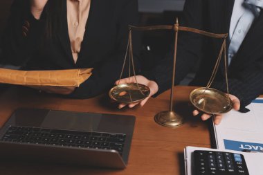 Ofisteki çekici genç avukat iş kadını ve avukatlar ofisdeki ahşap masada pirinç pullu kağıtları tartışıyorlar. Hukuk, hukuk hizmetleri, danışmanlık, Adalet ve emlak kavramı.