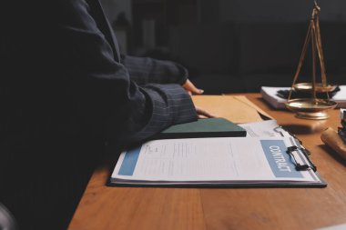 Ofisteki çekici genç avukat iş kadını ve avukatlar ofisdeki ahşap masada pirinç pullu kağıtları tartışıyorlar. Hukuk, hukuk hizmetleri, danışmanlık, Adalet ve emlak kavramı.