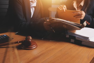 Ofisteki çekici genç avukat iş kadını ve avukatlar ofisdeki ahşap masada pirinç pullu kağıtları tartışıyorlar. Hukuk, hukuk hizmetleri, danışmanlık, Adalet ve emlak kavramı.