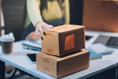 Girişim KOBİ küçük işletme girişimcisi önlük giyen Asyalı kadın dizüstü bilgisayar ve kutu kullanarak çevrimiçi müşterilere, çevrimiçi sme iş fikirlerine satış hazırlamak için siparişleri alır ve gözden geçirir.