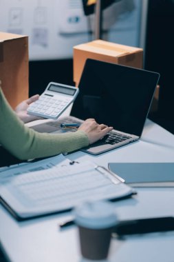 Girişim KOBİ küçük işletme girişimcisi önlük giyen Asyalı kadın dizüstü bilgisayar ve kutu kullanarak çevrimiçi müşterilere, çevrimiçi sme iş fikirlerine satış hazırlamak için siparişleri alır ve gözden geçirir.