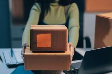 Girişim KOBİ küçük işletme girişimcisi önlük giyen Asyalı kadın dizüstü bilgisayar ve kutu kullanarak çevrimiçi müşterilere, çevrimiçi sme iş fikirlerine satış hazırlamak için siparişleri alır ve gözden geçirir.