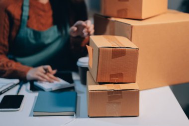 Girişim KOBİ küçük işletme girişimcisi önlük giyen Asyalı kadın dizüstü bilgisayar ve kutu kullanarak çevrimiçi müşterilere, çevrimiçi sme iş fikirlerine satış hazırlamak için siparişleri alır ve gözden geçirir.