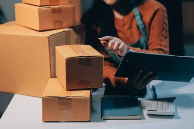 Girişim KOBİ küçük işletme girişimcisi önlük giyen Asyalı kadın dizüstü bilgisayar ve kutu kullanarak çevrimiçi müşterilere, çevrimiçi sme iş fikirlerine satış hazırlamak için siparişleri alır ve gözden geçirir.