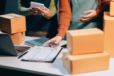 Girişim KOBİ küçük işletme girişimcisi önlük giyen Asyalı kadın dizüstü bilgisayar ve kutu kullanarak çevrimiçi müşterilere, çevrimiçi sme iş fikirlerine satış hazırlamak için siparişleri alır ve gözden geçirir.