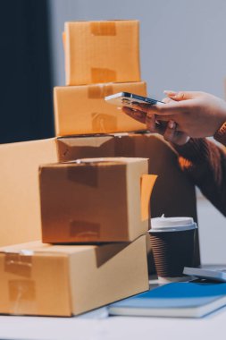 Girişim KOBİ küçük işletme girişimcisi önlük giyen Asyalı kadın dizüstü bilgisayar ve kutu kullanarak çevrimiçi müşterilere, çevrimiçi sme iş fikirlerine satış hazırlamak için siparişleri alır ve gözden geçirir.