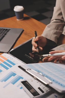 Group of confident business people point to graphs and charts to analyze market data, balance sheet, account, net profit to plan new sales strategies to increase production capacity.