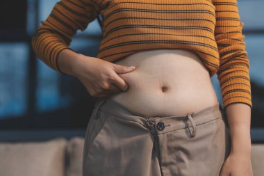 Şişman karnına dokunup sıkarken çekilmiş bir fotoğraf..