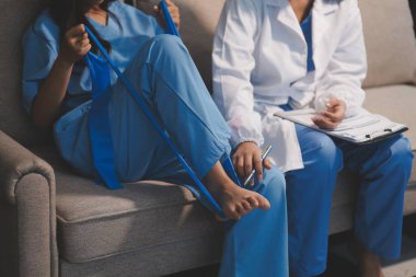 Kendine güvenen fizyoterapist, hastanın bacağını klinik odasında gerdirerek direnç bandı kullanmasına yardım ediyor..