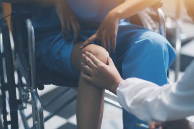 Kadın bir doktor, eklem iltihabı nedeniyle diz ağrısı olan yaşlı bir hastayı muayene eder. Hastaya iyileşme sürecinde yardım ediliyor, ağrı yönetimi ve hareket kabiliyetinin iyileştirilmesi üzerinde duruluyor..