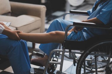 Kadın bir doktor, eklem iltihabı nedeniyle diz ağrısı olan yaşlı bir hastayı muayene eder. Hastaya iyileşme sürecinde yardım ediliyor, ağrı yönetimi ve hareket kabiliyetinin iyileştirilmesi üzerinde duruluyor..