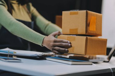 Girişim KOBİ küçük işletme girişimcisi önlük giyen Asyalı kadın dizüstü bilgisayar ve kutu kullanarak çevrimiçi müşterilere, çevrimiçi sme iş fikirlerine satış hazırlamak için siparişleri alır ve gözden geçirir.