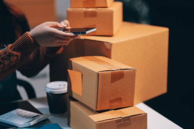 Girişim KOBİ küçük işletme girişimcisi önlük giyen Asyalı kadın dizüstü bilgisayar ve kutu kullanarak çevrimiçi müşterilere, çevrimiçi sme iş fikirlerine satış hazırlamak için siparişleri alır ve gözden geçirir.