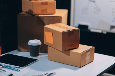 Girişim KOBİ küçük işletme girişimcisi önlük giyen Asyalı kadın dizüstü bilgisayar ve kutu kullanarak çevrimiçi müşterilere, çevrimiçi sme iş fikirlerine satış hazırlamak için siparişleri alır ve gözden geçirir.