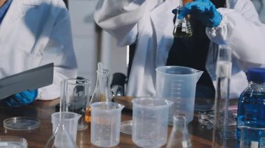 Koruyucu eldivenlerdeki bilim adamları sıvı tüpler tutuyorlar.