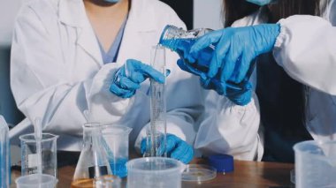 Koruyucu gözlüklü bilim adamı laboratuarda sıvı tüpü tutuyor.