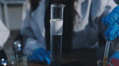 Bilim adamı elinde bir bardak su tutuyor.