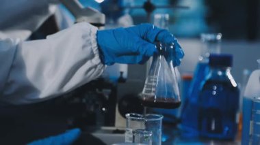 Laboratuvar ekipmanları. Laboratuvarda mikroskopla çalışan koruyucu eldivenli bir bilim adamı..