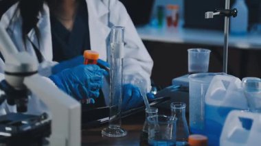 Mavi üniformalı laboratuvar asistanı elinde kimyasal sıvıyla laboratuvar asistanı..