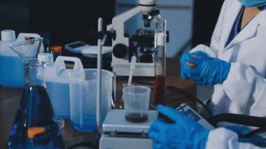 Laboratuvar asistanı laboratuvarda bir bardak sıvı tutuyor, yakın plan..