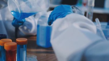 Laboratuvarda tüpü tutan bilimadamlarının yakınına.