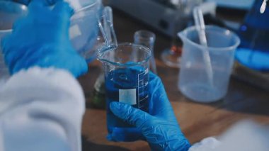 Yakın plan - bir laboratuvar çalışanı deney tüpü ile bir tüp tutuyor