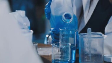 Yakın plan - laboratuvar bardağında bir sıvıyla test tüplerini tutan bir elin fotoğrafı.