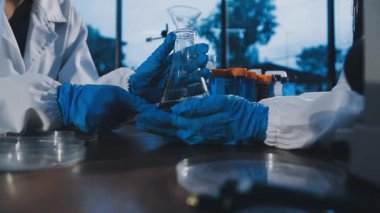 Laboratuvar asistanı elinde matara ve kimyasal sıvı tutuyor..