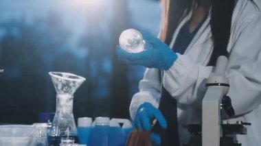 Laboratuvarda mikroskoba bakan laboratuvar önlüklü genç bilim adamı.