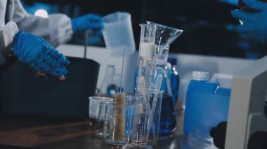 Koruyucu kıyafetli bilim adamı laboratuarda bir deney yapıyor..