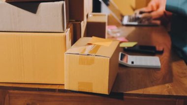 Teslimat. Evin arka planında karton kutuları ve dizüstü bilgisayarı olan bir adam..