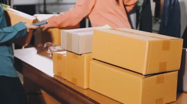 Kadın elinde karton kutular, dükkanda bir paket kutusu var. İnternet üzerinden iş hizmeti.