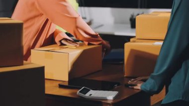 Deponun müşterileri için akıllı telefon ve dizüstü bilgisayar kullanan üniformalı bir teslimatçı.