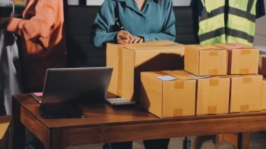 Karton kutular ve dizüstü bilgisayarla paket taşıyan teslimatçı..