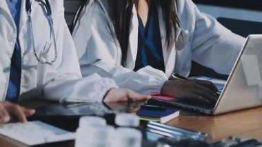 Genç bayan doktor ofiste dizüstü bilgisayar kullanıyor.