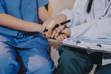 Doktor, klinikteki masada otururken hasta kadına güven veriyor, sadece eller. İlaç ve en iyi hizmet